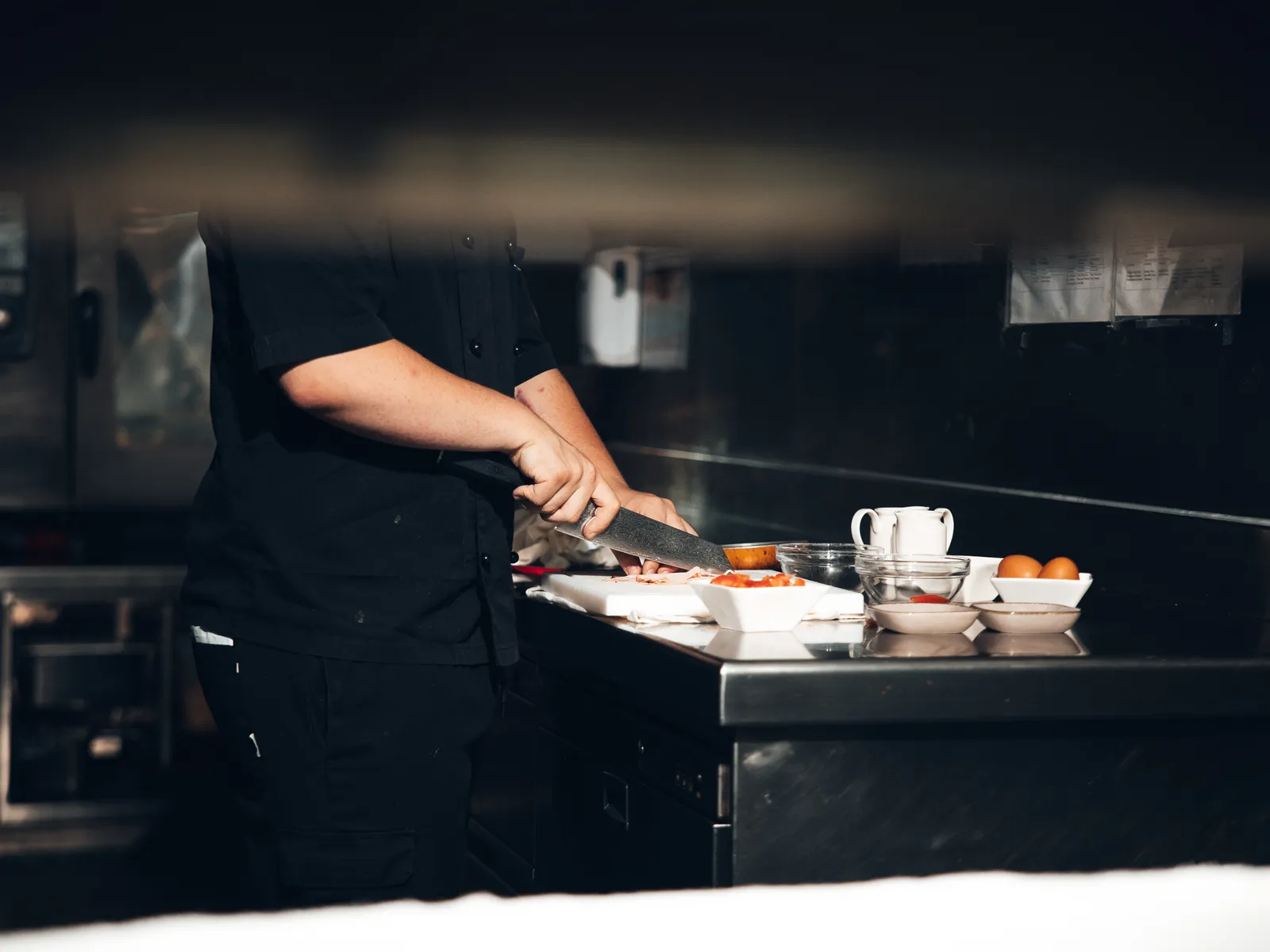 Chef cutting vegetables on a cutting board in a kitchen