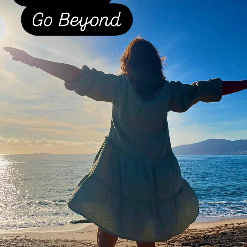 Rückenansicht Frau am Meer mit ausgebreiteten Armen