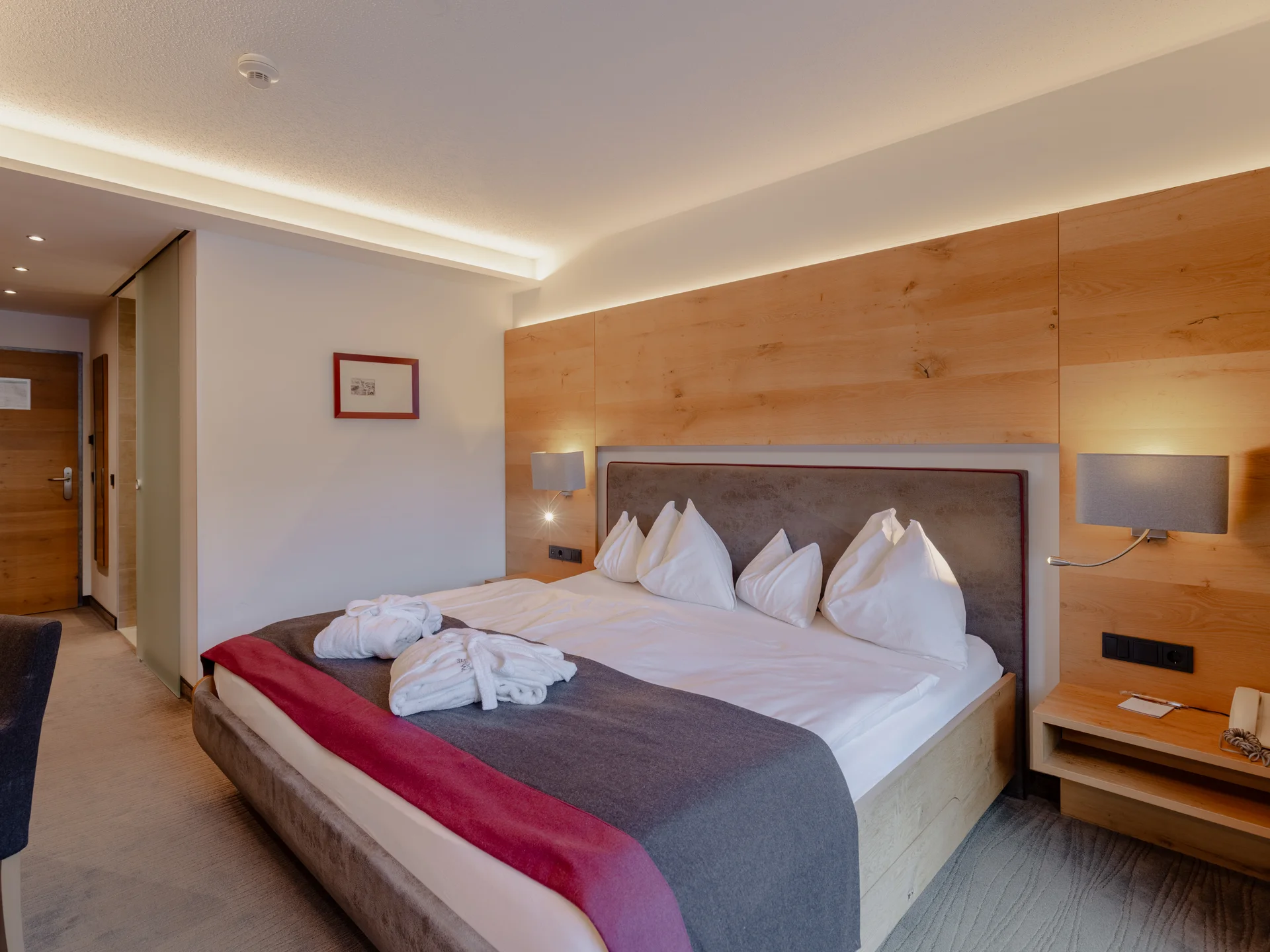 Modern hotel room with a large bed and wood paneling