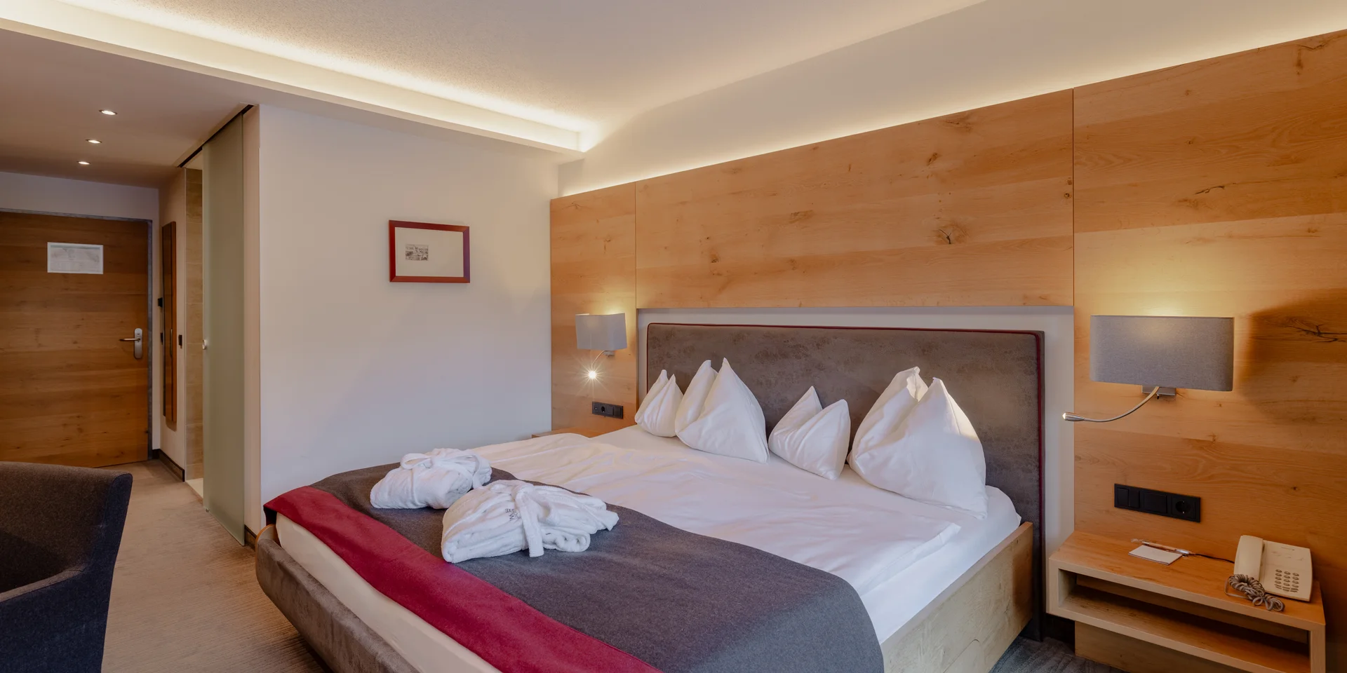 Modernes Hotelzimmer mit großem Bett und Holzvertäfelung