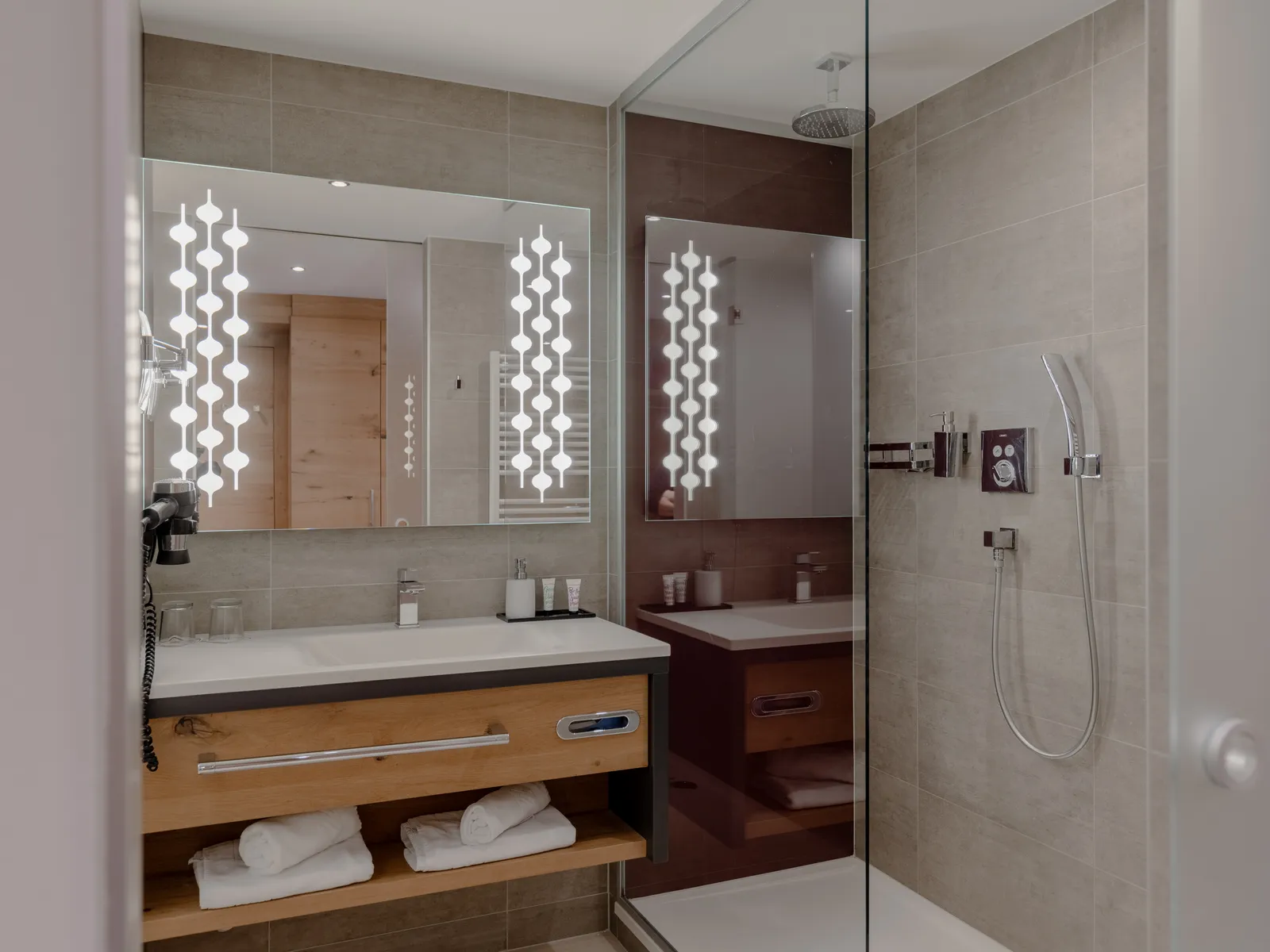 Elegantes Hotelbadezimmer mit beleuchtetem Spiegel und Dusche