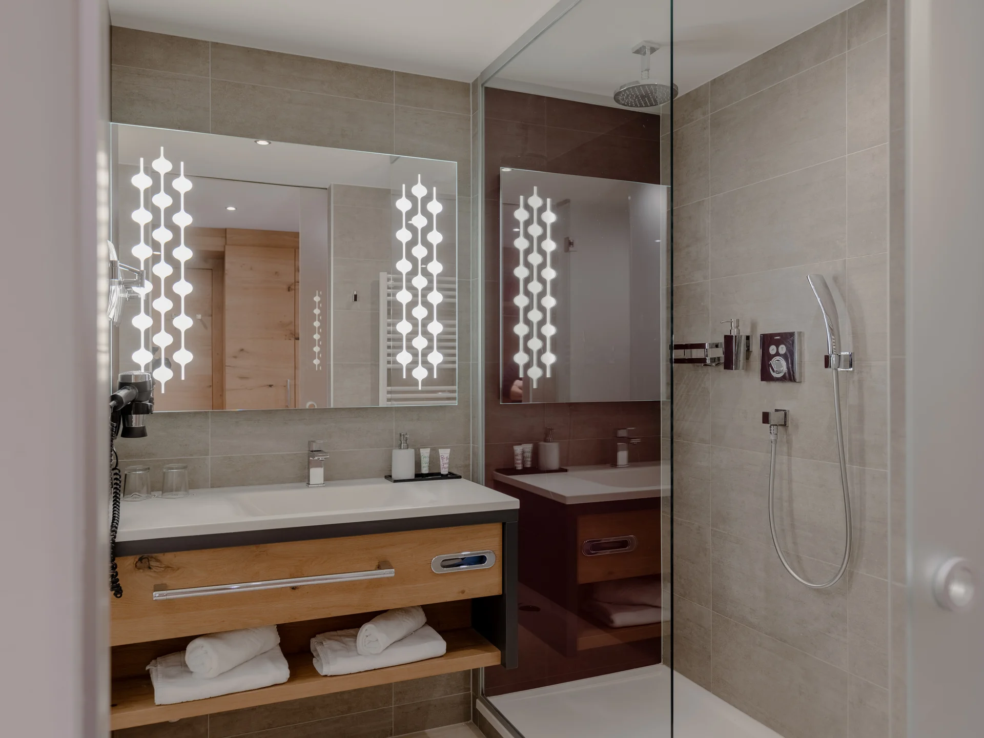 Elegantes Hotelbadezimmer mit beleuchtetem Spiegel und Dusche