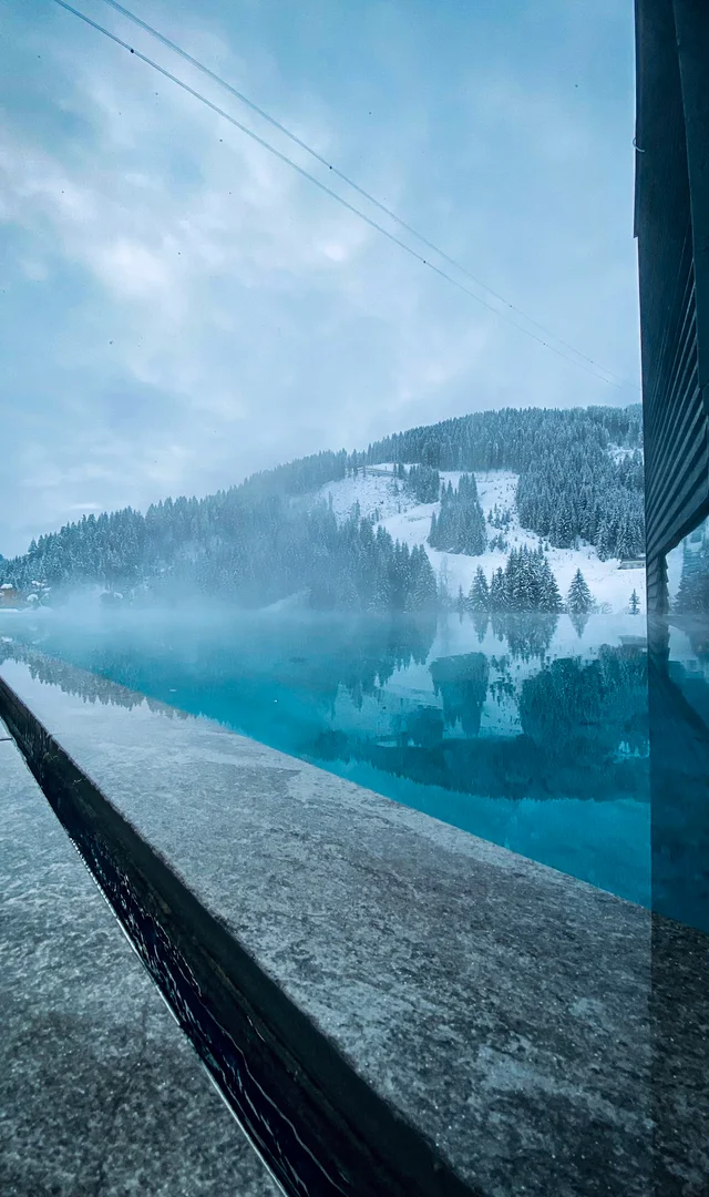 Turquoise pool in front of a snowy mountain landscape on a cloudy winter day