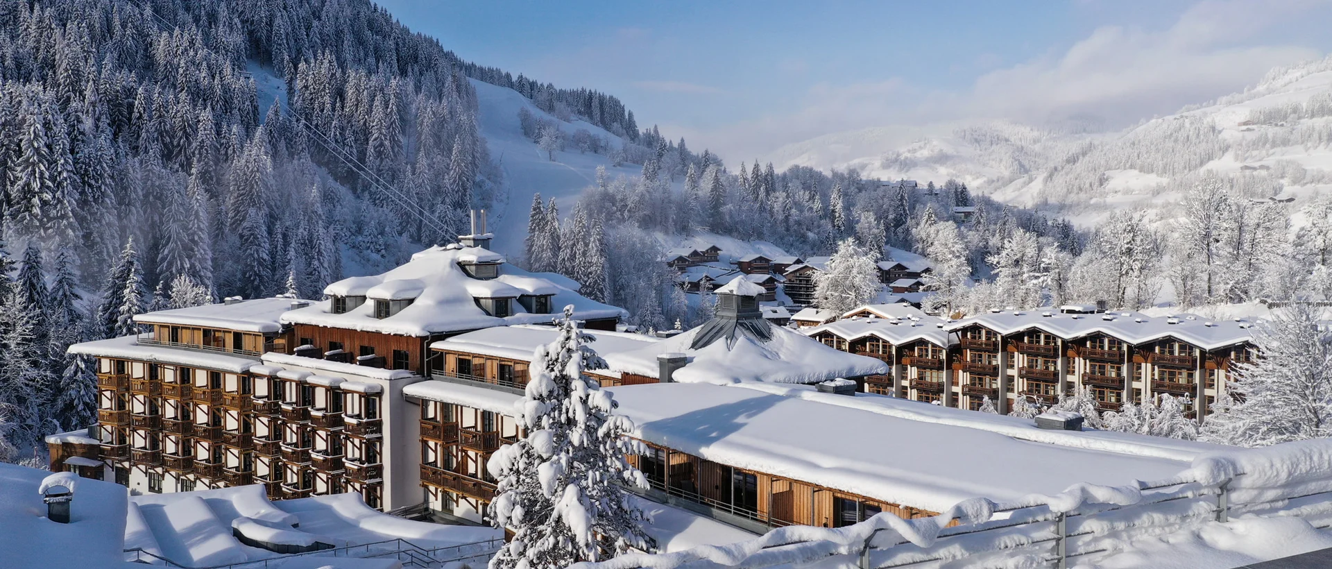 Snow-covered Sporthotel Wagrain in front of snowy mountain landscape under blue sky