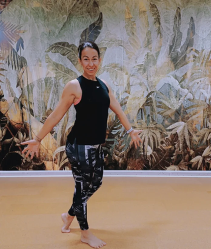 Lächelnde Frau in Sportkleidung vor Dschungelwand