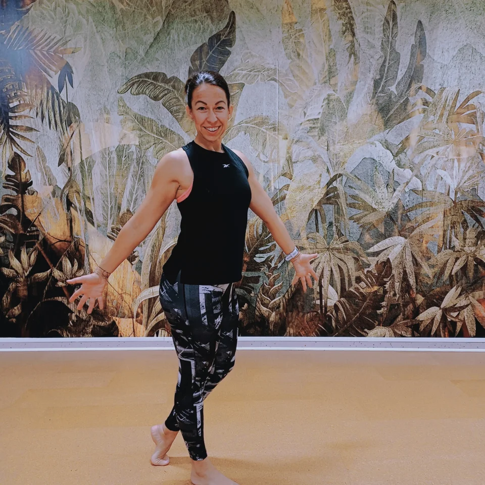 Smiling woman in sportswear in front of a jungle wall