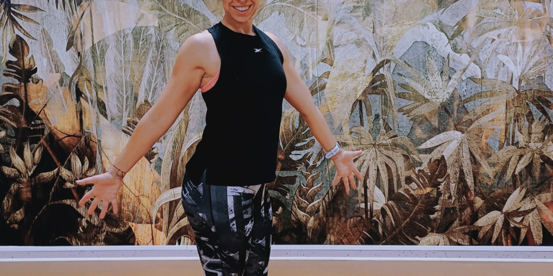 Smiling woman in sportswear in front of a jungle wall