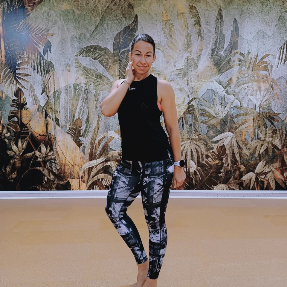 Smiling woman in sportswear in front of a jungle wall