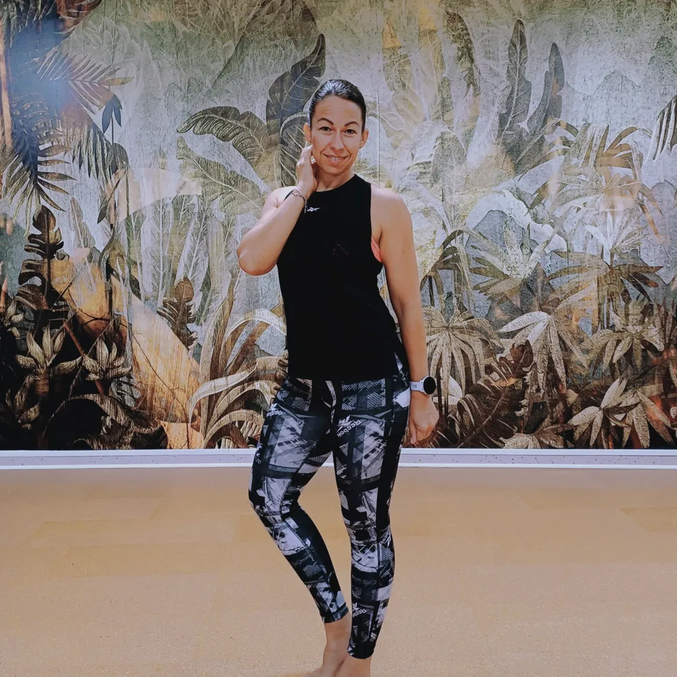 Smiling woman in sportswear in front of a jungle wall