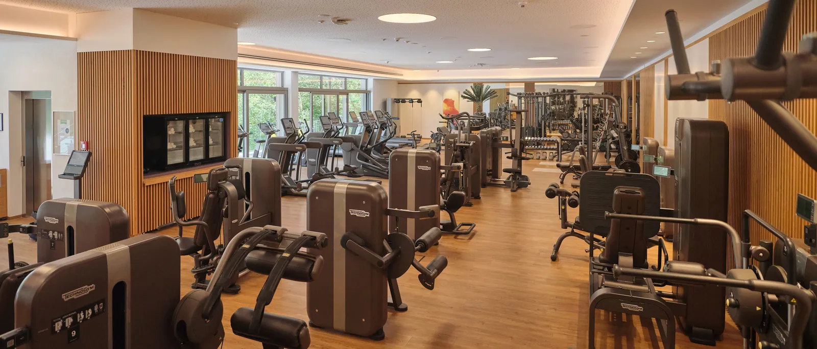 Bright fitness room with many machines and large windows