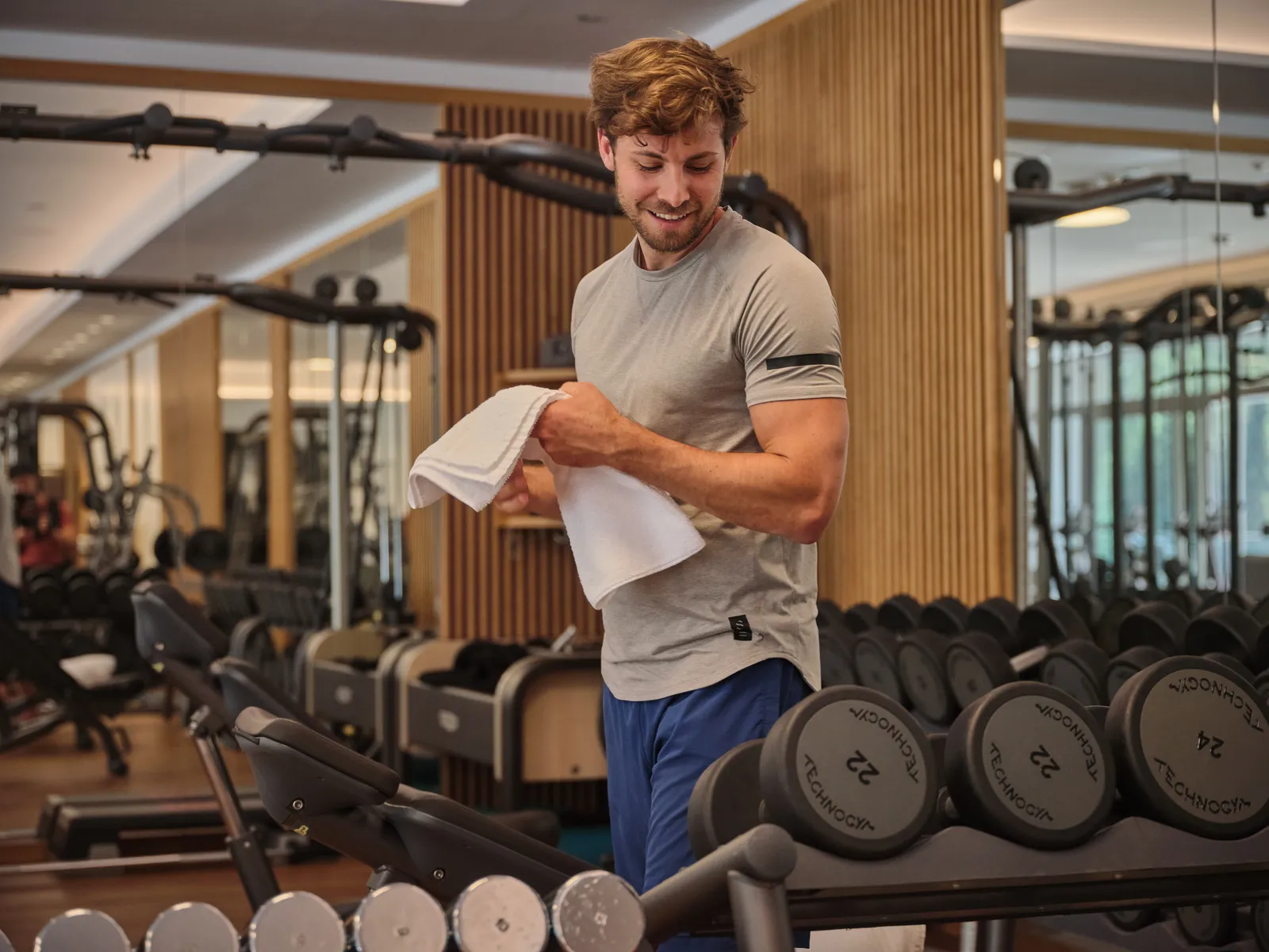 Man in the gym with towel and dumbbells