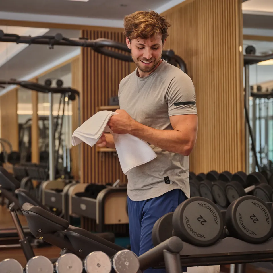Mann im Fitnessstudio mit Handtuch und Hanteln