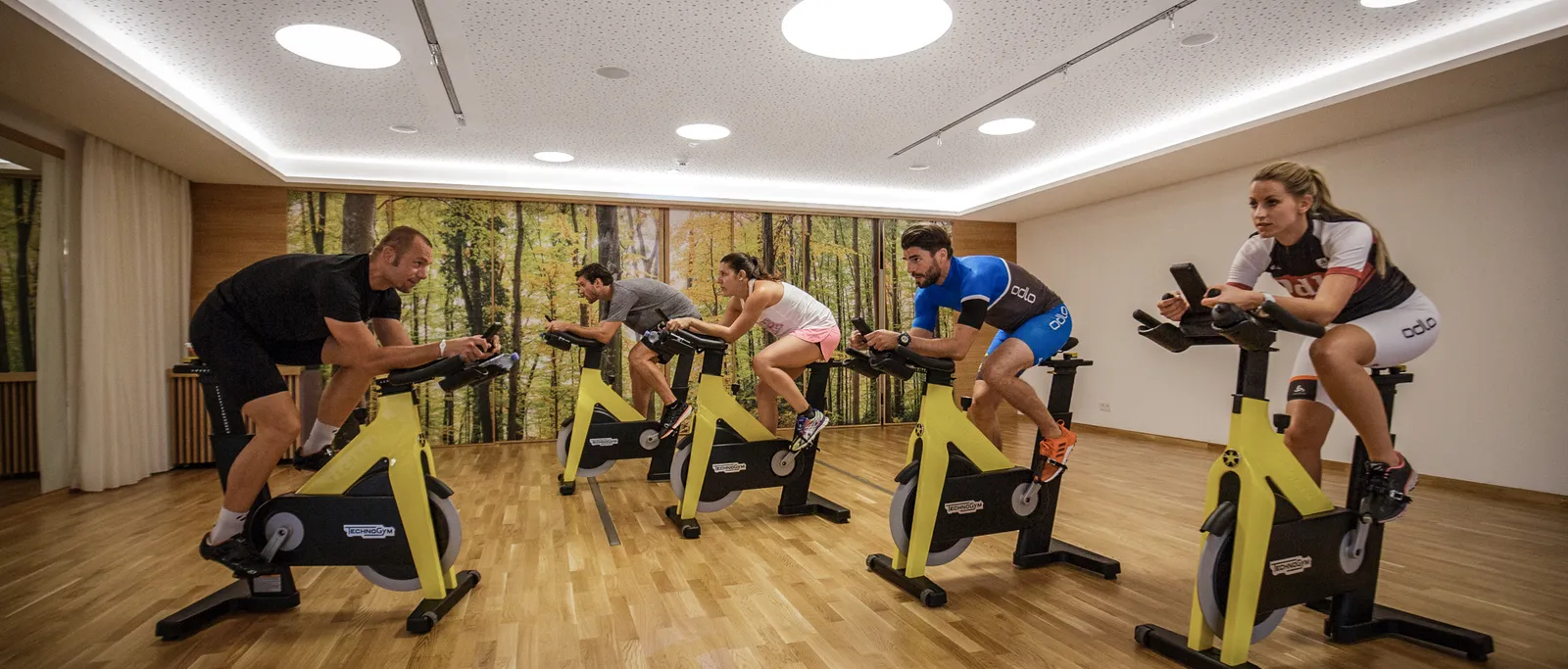 Fitness room with several people on yellow spinning bikes