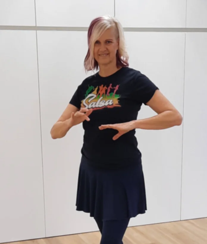 Frau in schwarzem T-Shirt und Rock tanzt mit erhobenen Händen