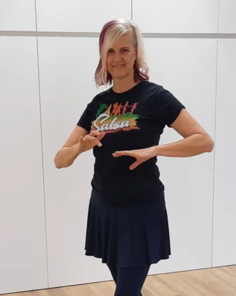Frau in schwarzem T-Shirt und Rock tanzt mit erhobenen Händen