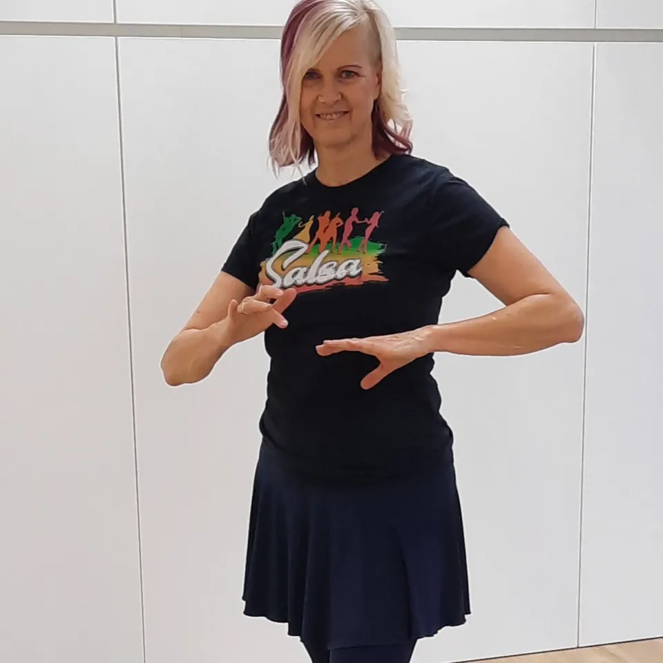 Woman in black T-shirt and skirt dancing with raised hands