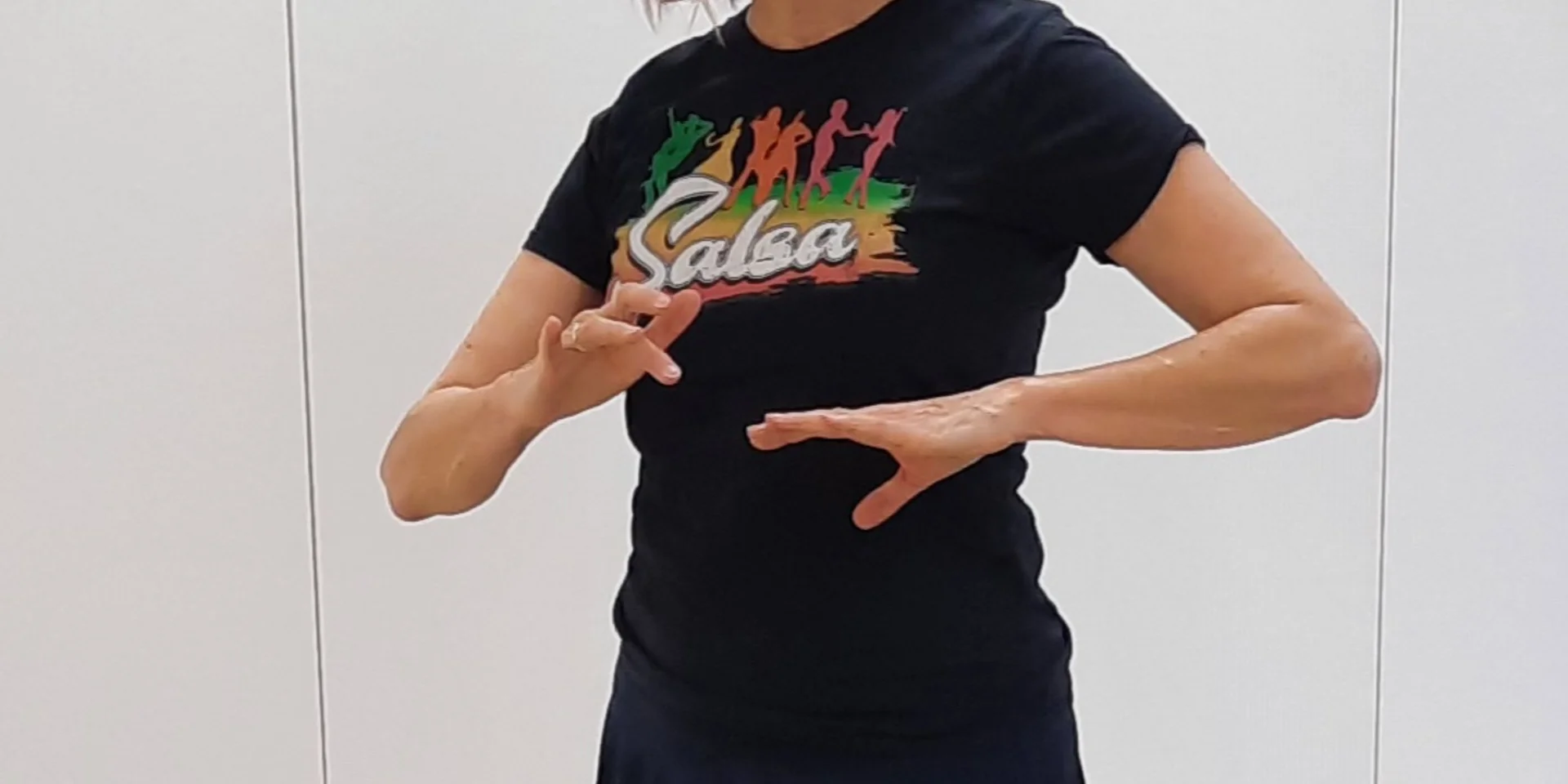 Frau in schwarzem T-Shirt und Rock tanzt mit erhobenen Händen