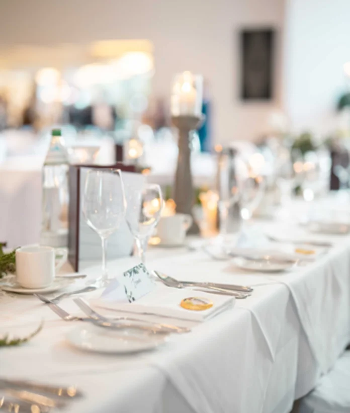 Wedding table set with white tablecloth, glasses, cutlery and candlesticks