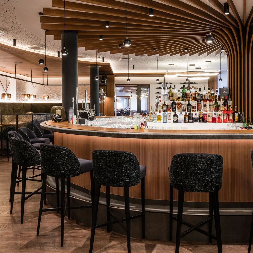 Elegante Bar mit dunklen Barhockern, Holztheke und Flaschenregal