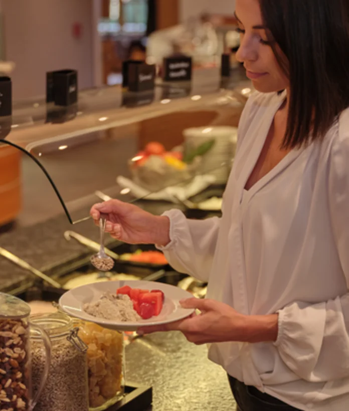 Woman takes food from the buffet onto a plate