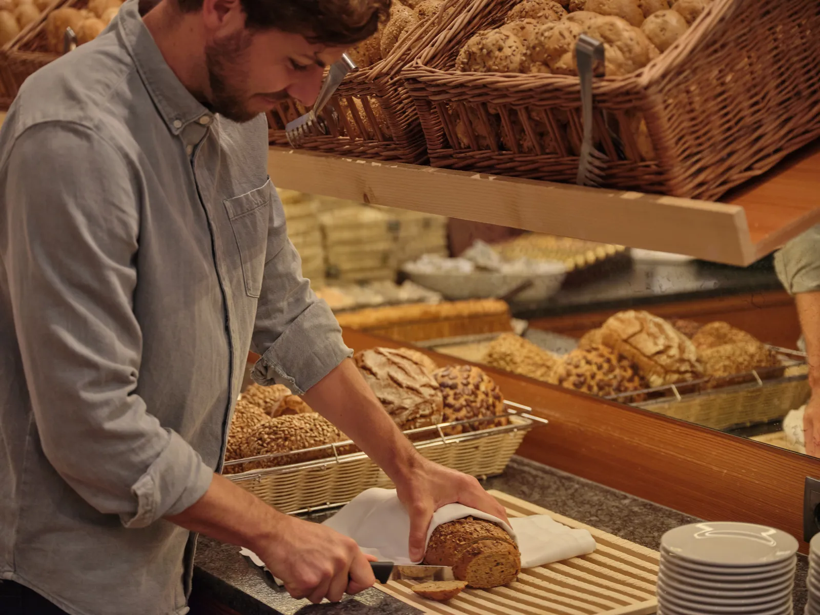 Mann schneidet Brot an einem Buffet mit Brotkörben