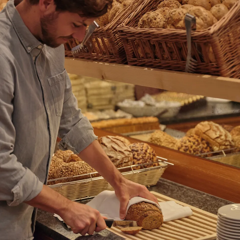 Mann schneidet Brot an einem Buffet mit Brotkörben
