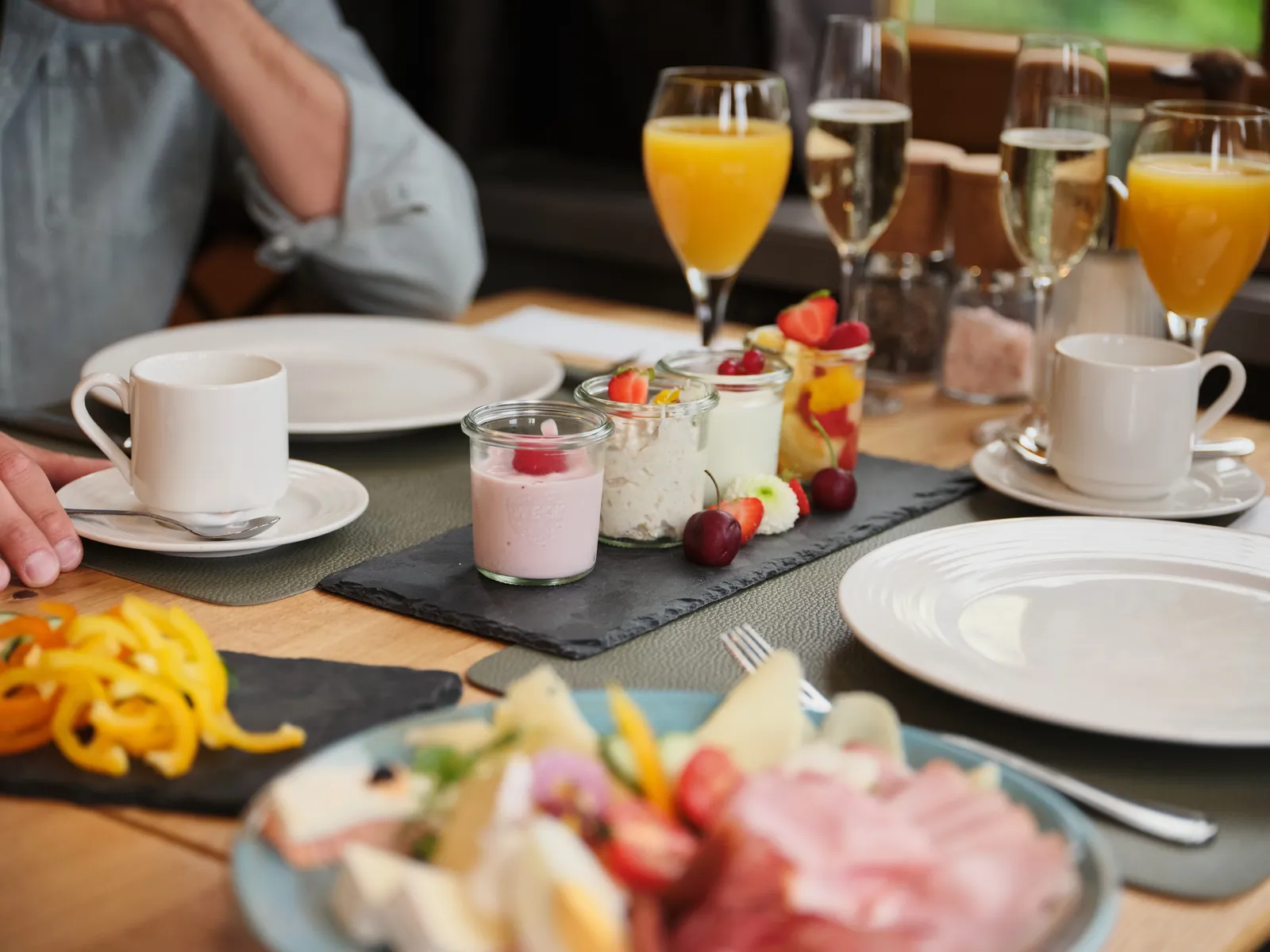 Gedeckter Frühstückstisch mit Joghurt, Obst, Saft und Sektgläsern im Sporthotel Wagrain