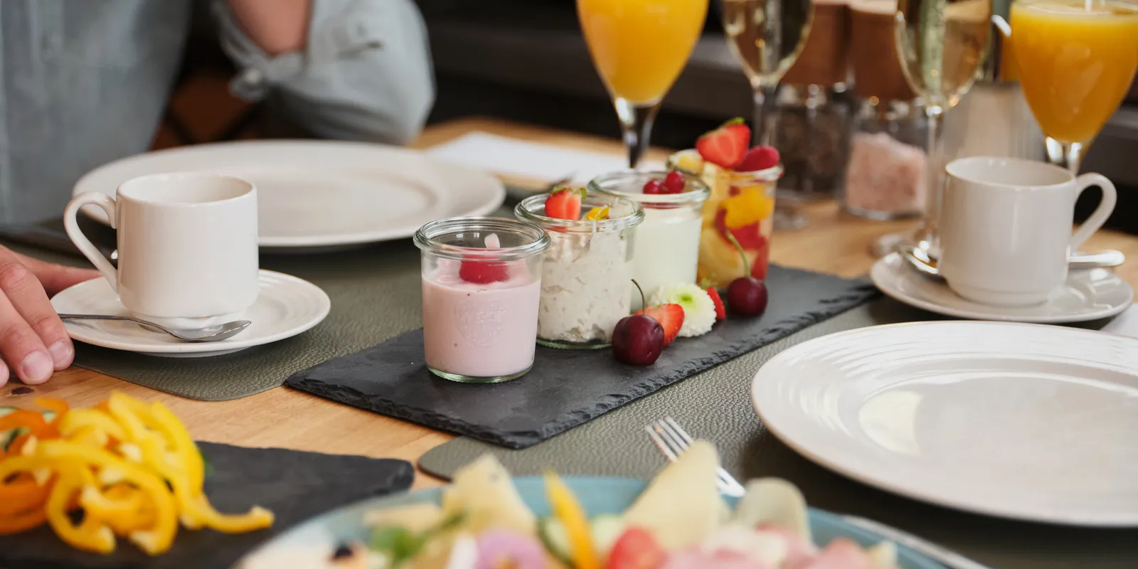Gedeckter Frühstückstisch mit Joghurt, Obst, Saft und Sektgläsern im Sporthotel Wagrain