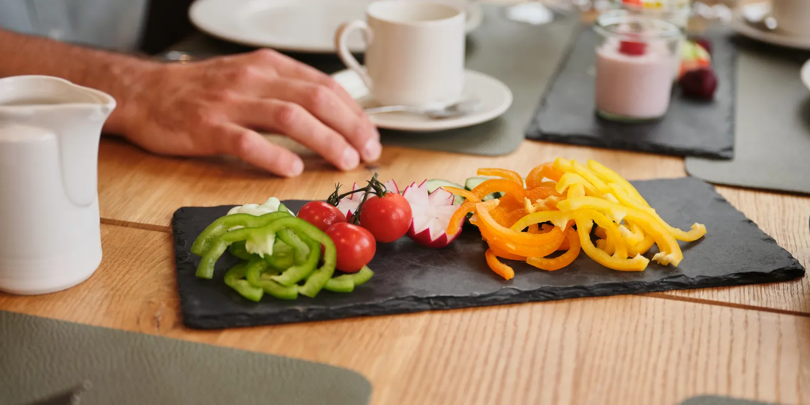 Frühstückstisch mit Gemüseplatte, Joghurt, Kaffee und Saft im Sporthotel Wagrain
