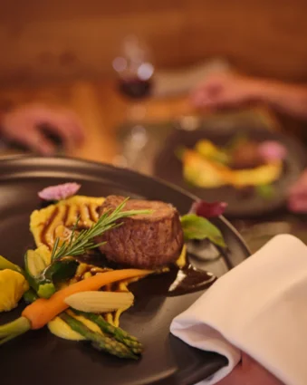 Meat dish with vegetables served on a dark plate in a restaurant