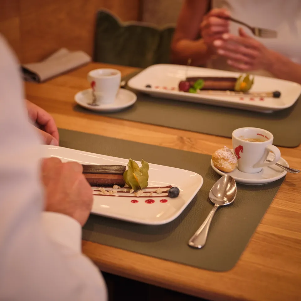 Dessertteller mit Schokoladenrolle, Physalis, Beeren und Espresso auf einem Holztisch