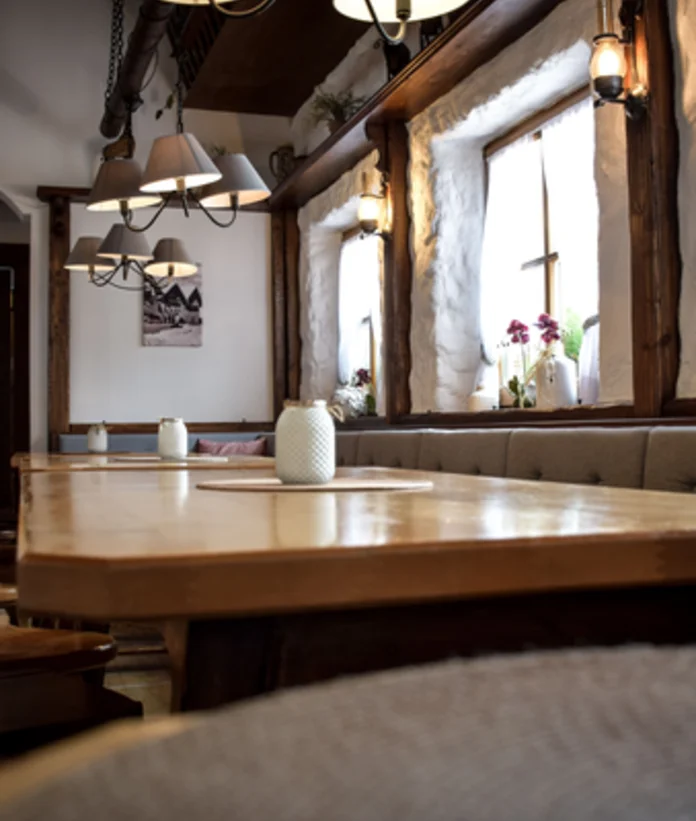 Rustikale Gaststube mit langem Holztisch, Fensterbank und Lampen