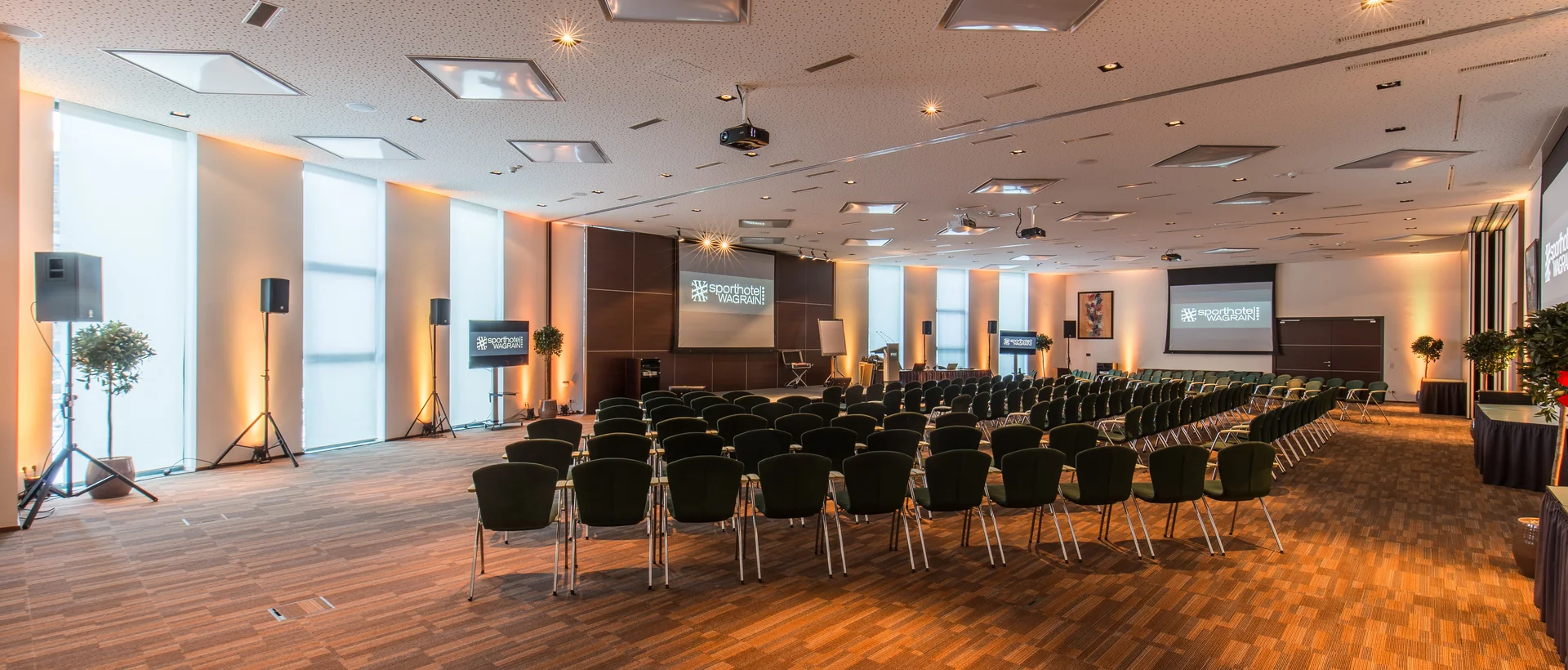 Seminarraum mit Stuhlreihen, Bühne und Leinwand im Sporthotel Wagrain