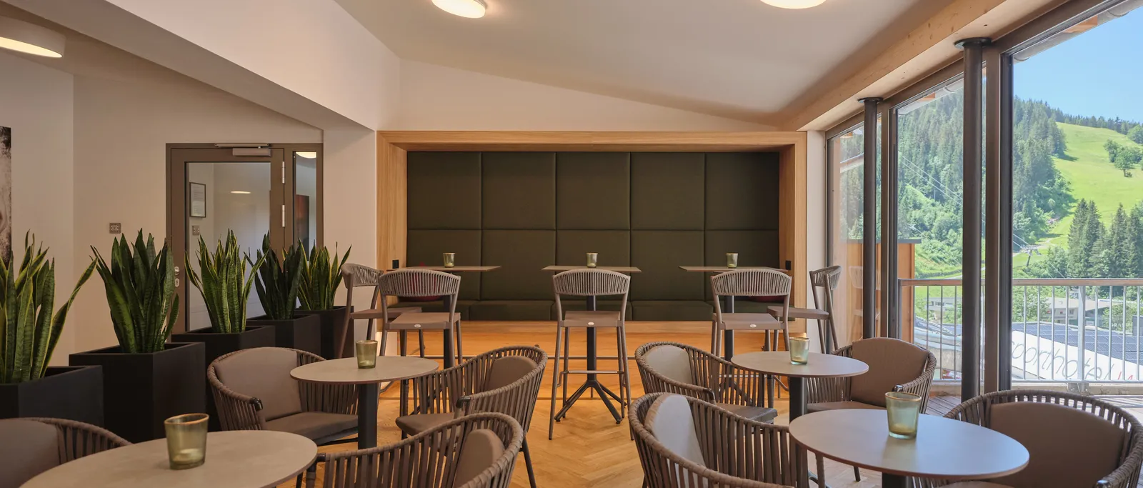 Bright room with tables, chairs and plants at the Sporthotel Wagrain