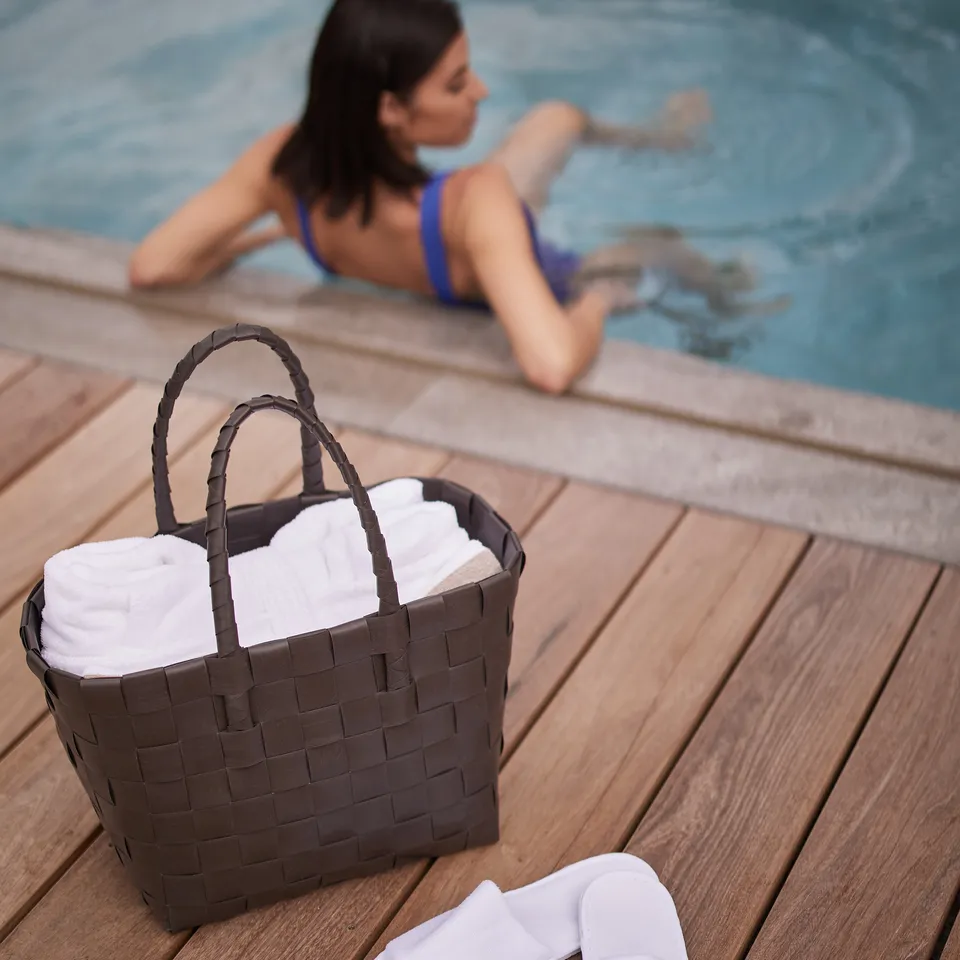 Frau im blauen Badeanzug am Pool, Korb mit Handtüchern im Vordergrund