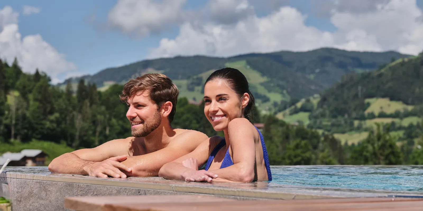 Paar im Pool mit Bergblick lächelt