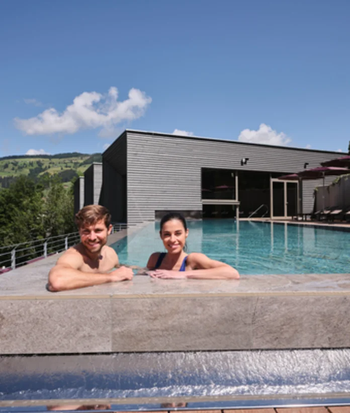 Paar im Außenpool vor dem Sporthotel Wagrain mit Bergblick