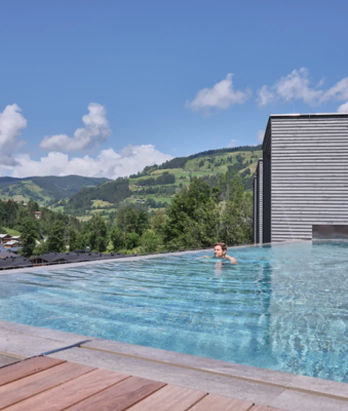 Swimming pool with person in front of mountain landscape under blue sky