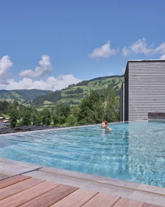 Swimming pool with person in front of mountain landscape under blue sky