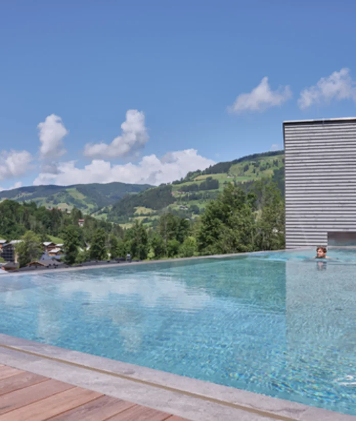 Pool overlooking green hills and blue skies at Sporthotel Wagrain