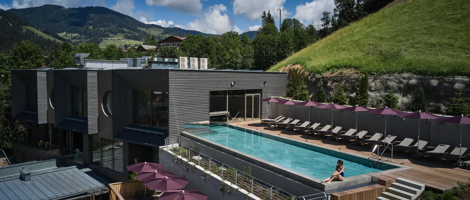 Sporthotel Wagrain with rooftop pool and sun loungers under parasols against a mountain backdrop