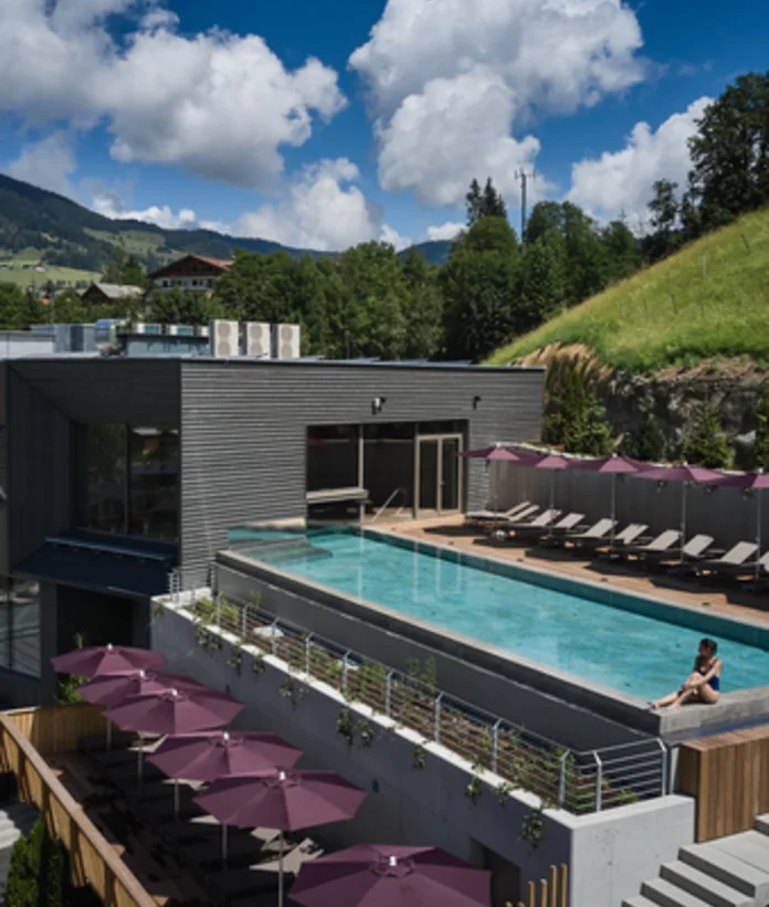 Sporthotel Wagrain with rooftop pool and sun loungers under parasols against a mountain backdrop