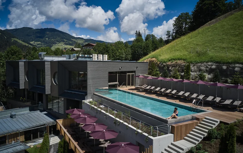Sporthotel Wagrain with rooftop pool and sun loungers under parasols against a mountain backdrop