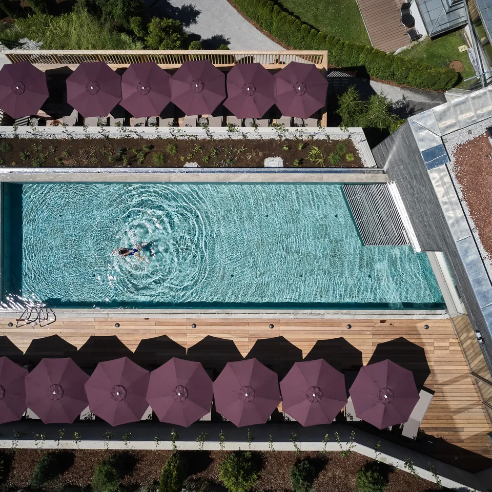 Draufsicht auf Hotelpool mit Liegen und Person im Wasser