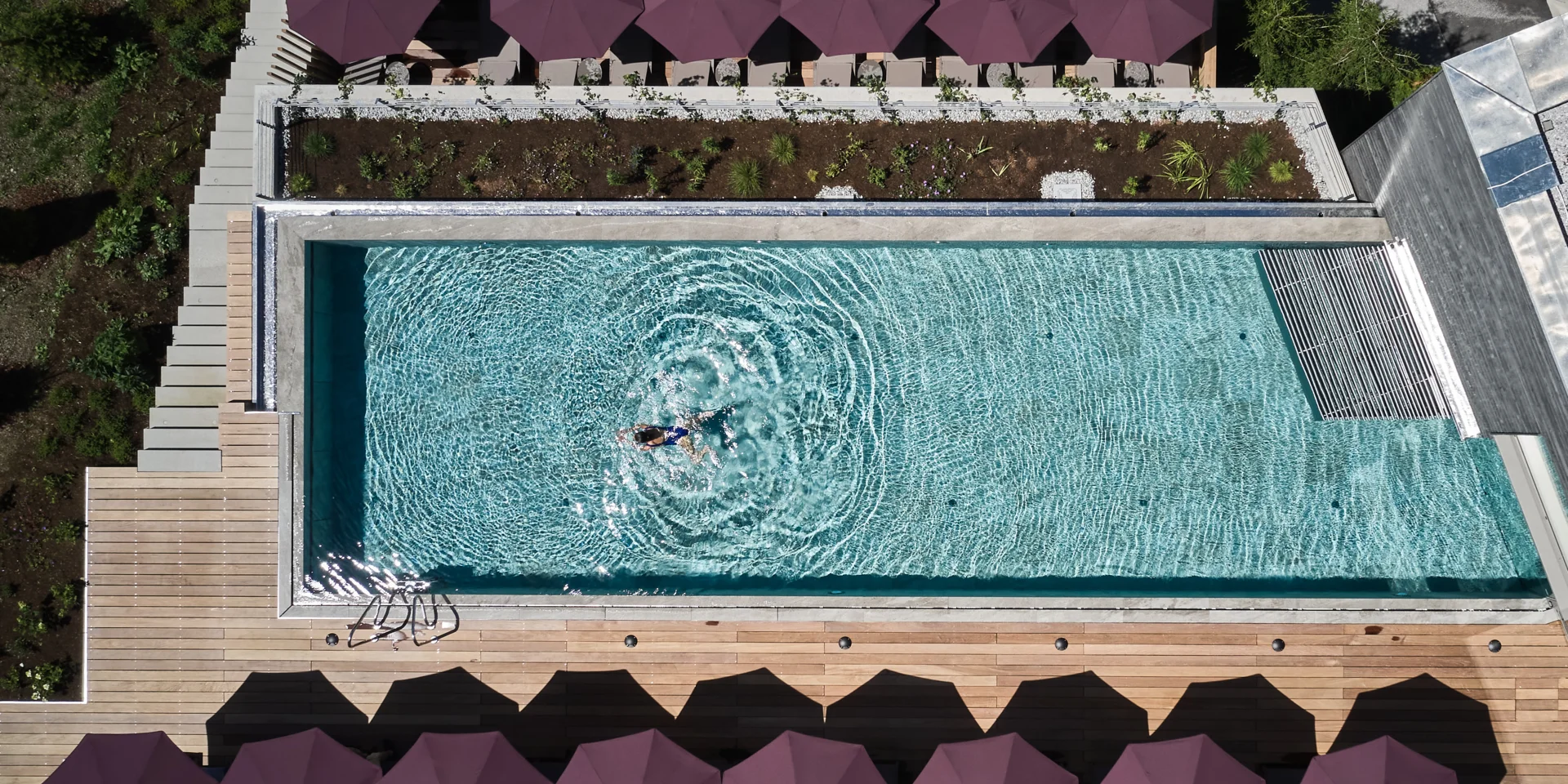 Draufsicht auf Hotelpool mit Liegen und Person im Wasser