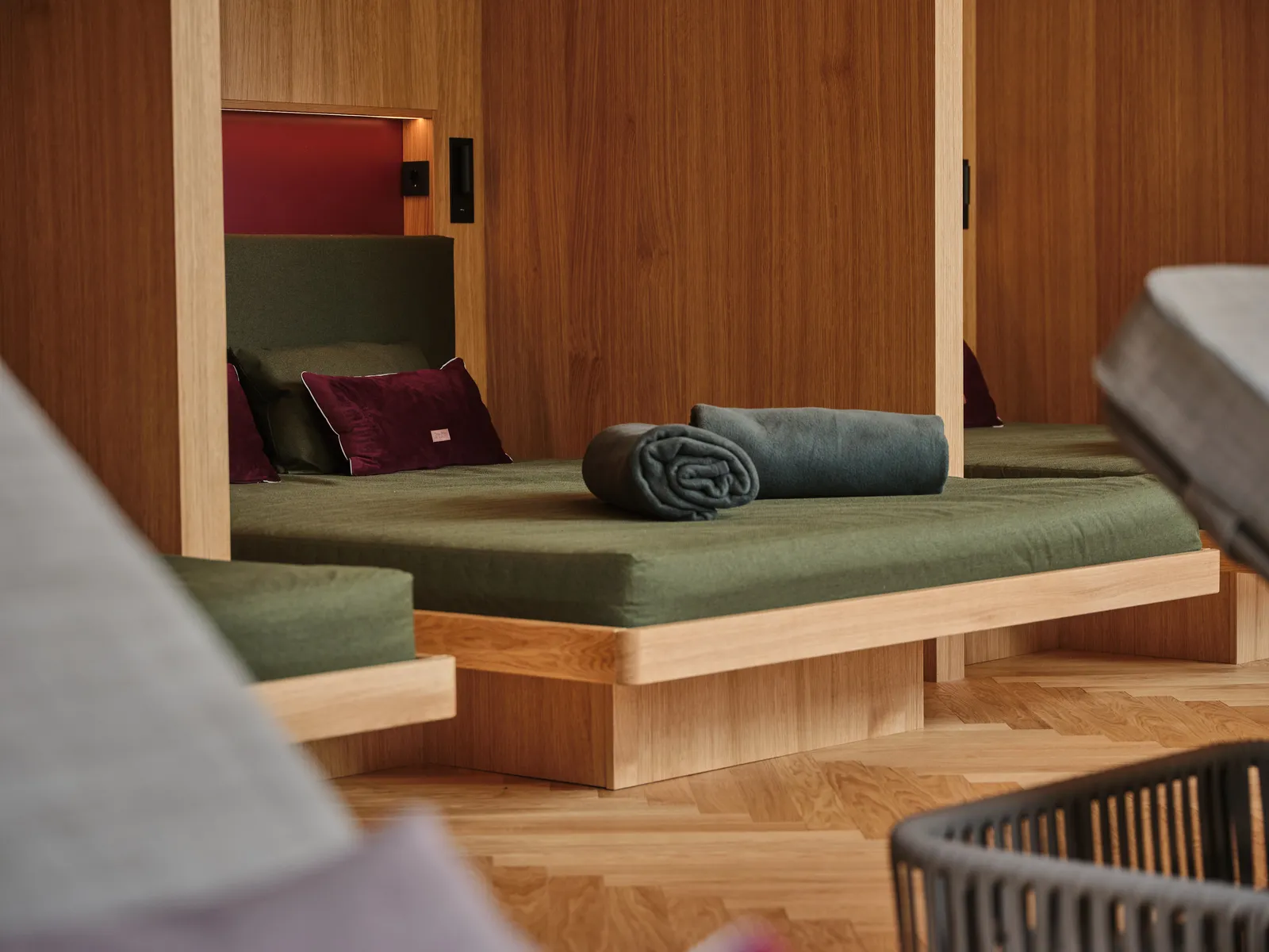 Wooden loungers with green cushions and rolled towels in a wellness area