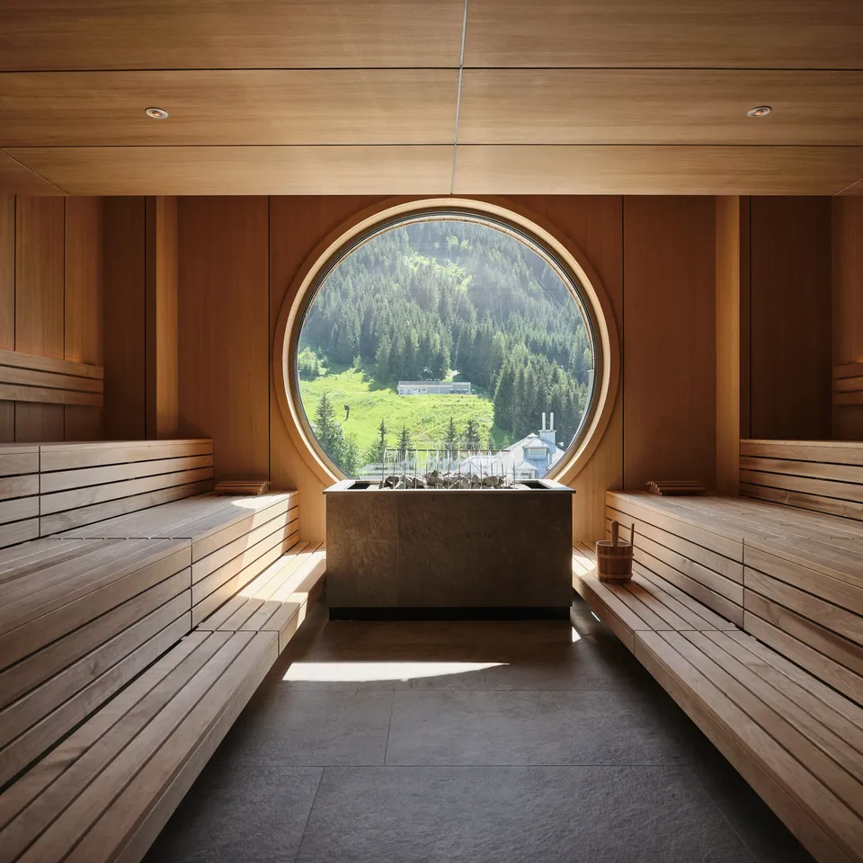 Wooden sauna with round window and view of green mountains