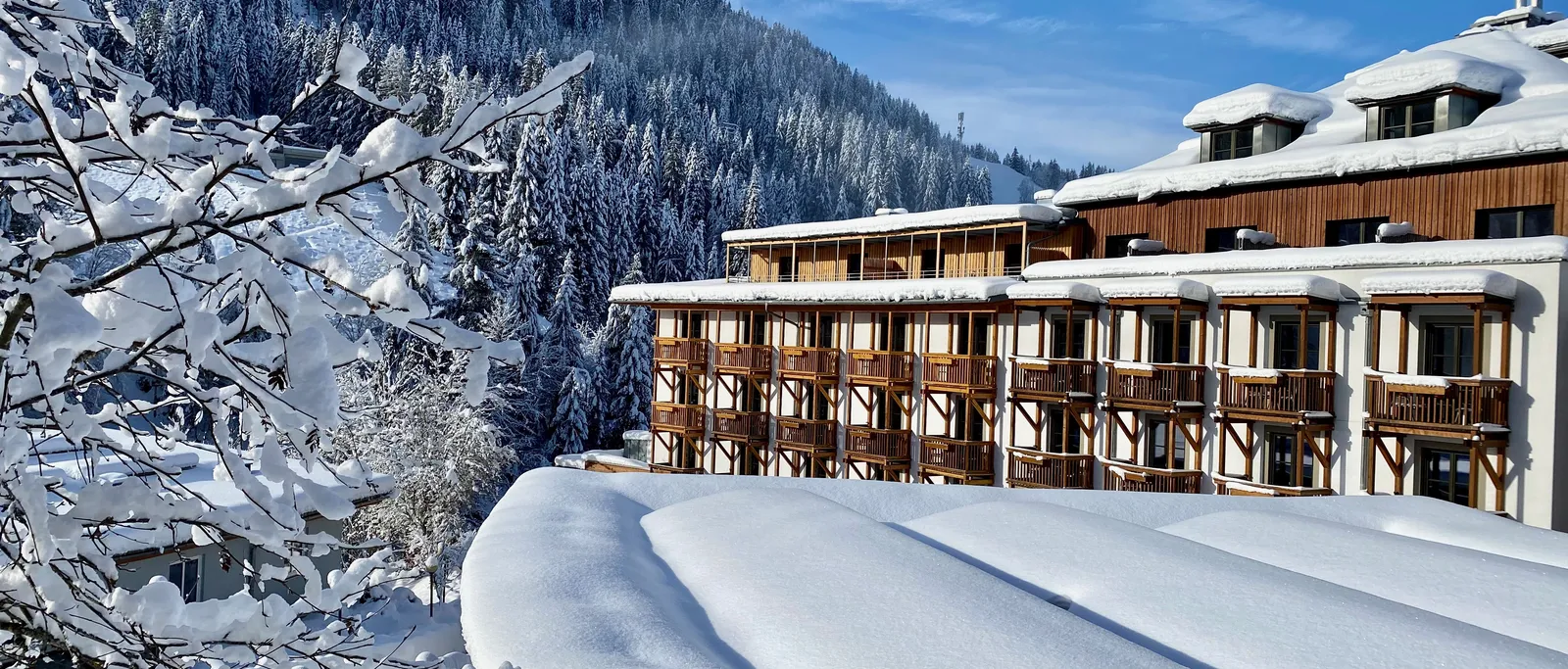 Sporthotel Wagrain in verschneiter Berglandschaft mit Tannenwald und blauem Himmel
