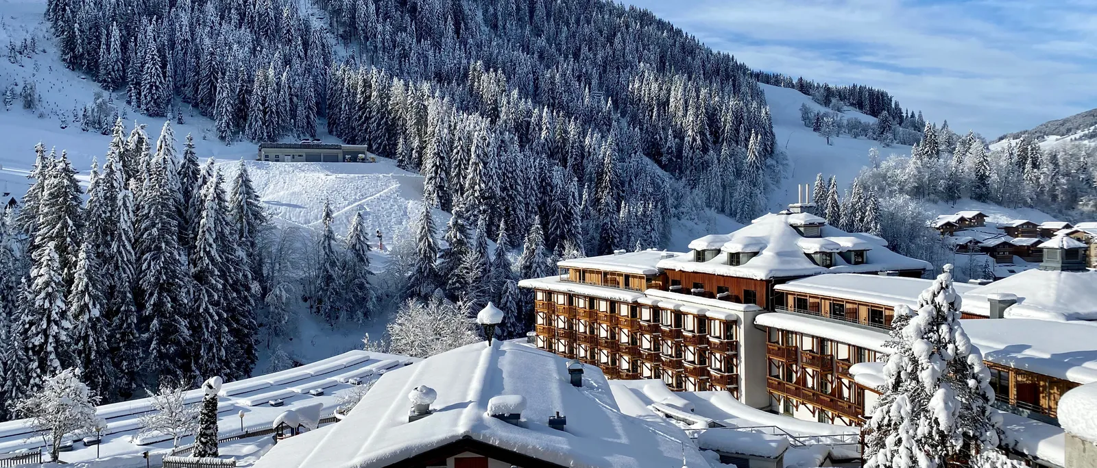 Sporthotel Wagrain  in winter in front of a snow-covered forest slope