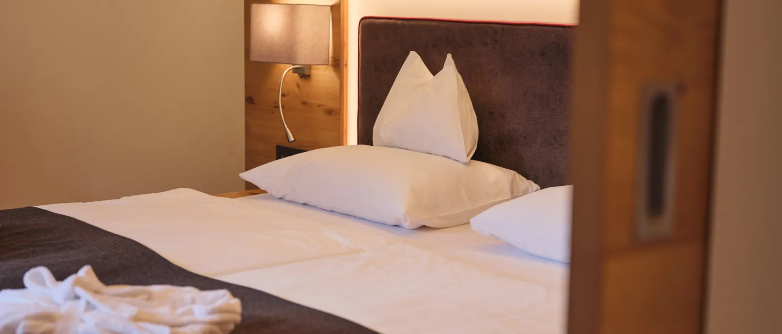 Hotel room with double bed, bedside lamp and wooden wall